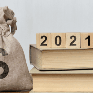 Blocks that spell out 2021 sitting on top of stack of books with money bag next to it