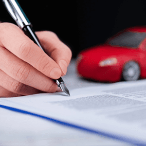 Person signing document with small toy car in background
