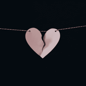 Paper heart ripped in half being held up by string