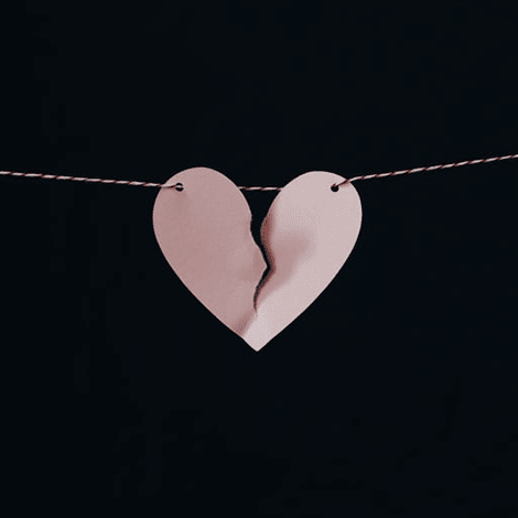 Paper heart ripped in half being held up by string