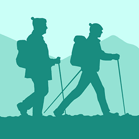 Two hikers walking together along path with mountains in background
