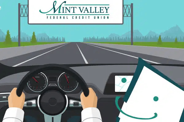 A driver holds a steering wheel with a GPS screen on the dashboard, driving towards a "Mint Valley Federal Credit Union" sign on a clear day.